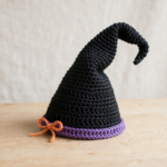 Finished crochet witch hat pattern: tall black hat with bent tip, purple band and orange bow