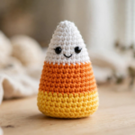 Finished crochet candy corn pattern amigurumi character with striped white, orange and yellow body and smiling face